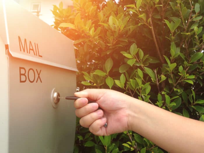 Hand unlocking a mailbox with a key