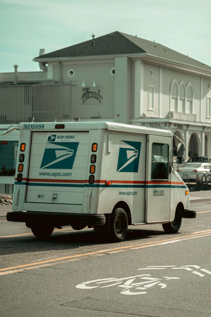 USPS mail delivery truck driving down a street